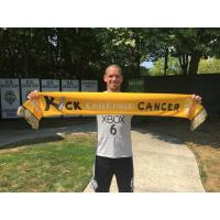 Seattle Sounders captain Ozzie Alonso poses with a Kick Childhood Cancer scarf